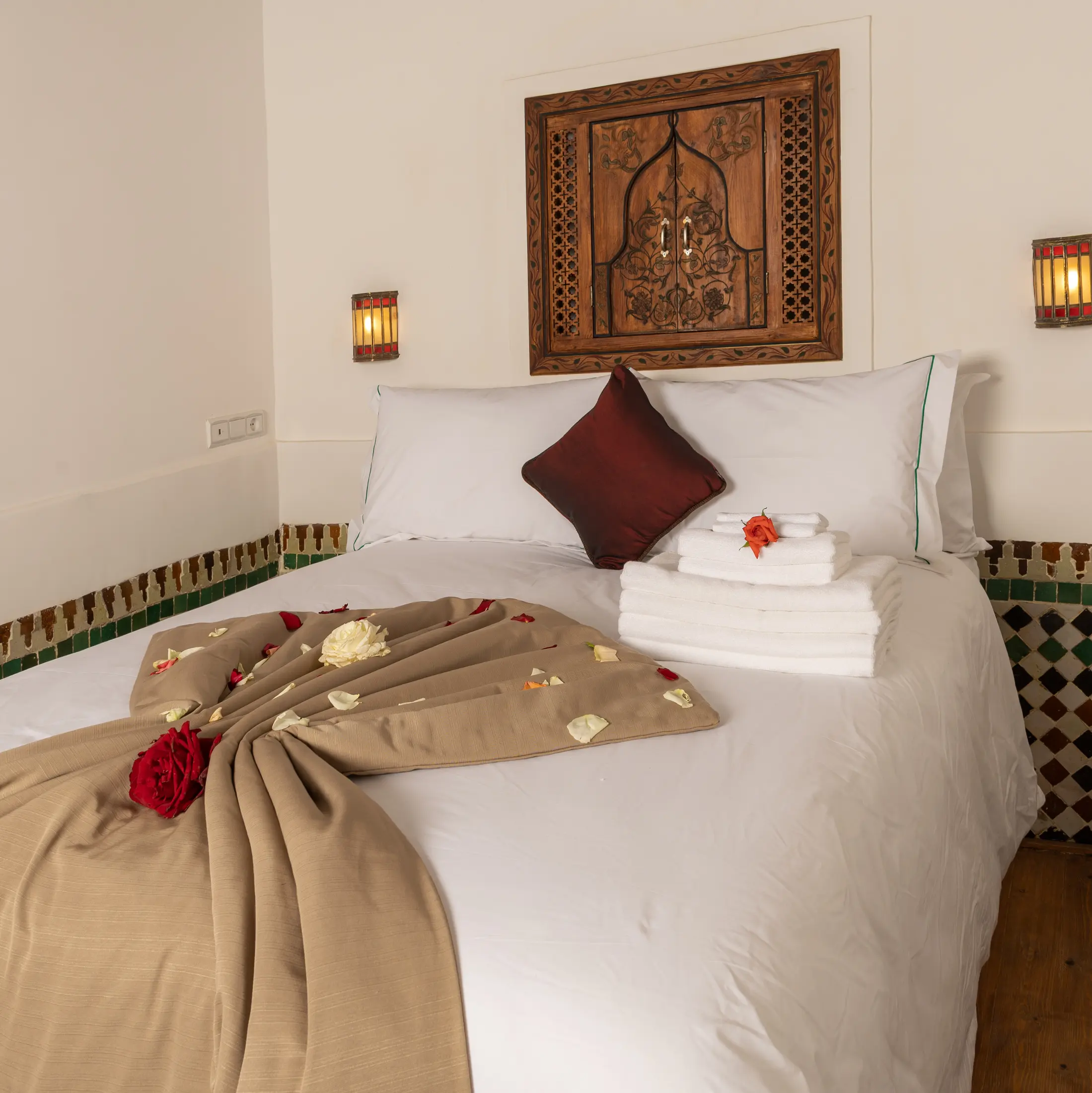 Double bed beneath a carved cedar panel and two lanterns