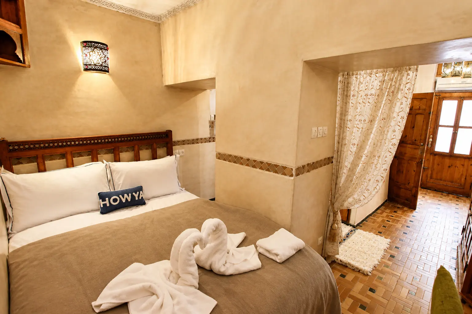 Double bed with folded towels beneath a carved wall lantern