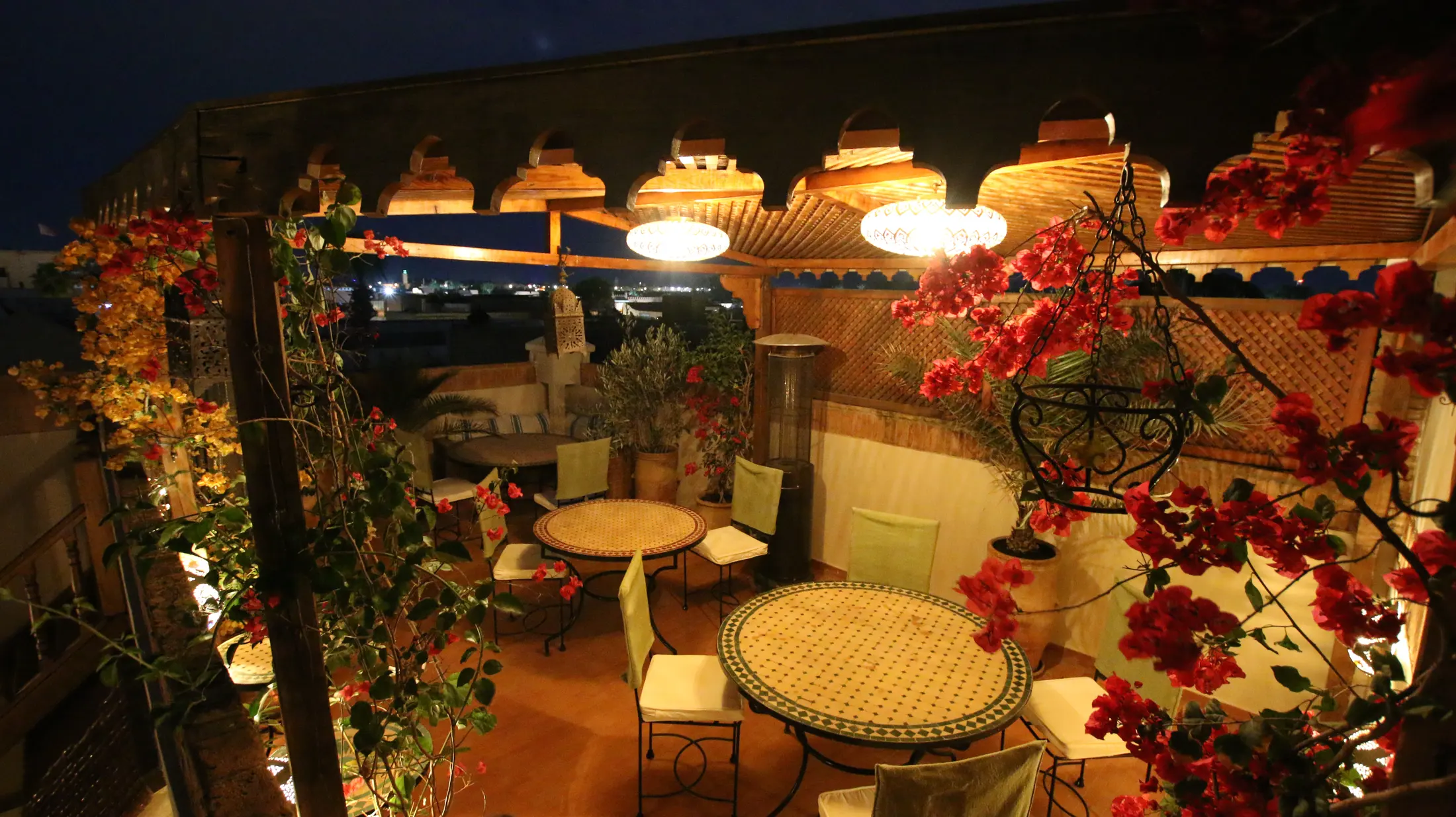 The Majlis Dining Terrace at night beneath lanterns and bougainvillea